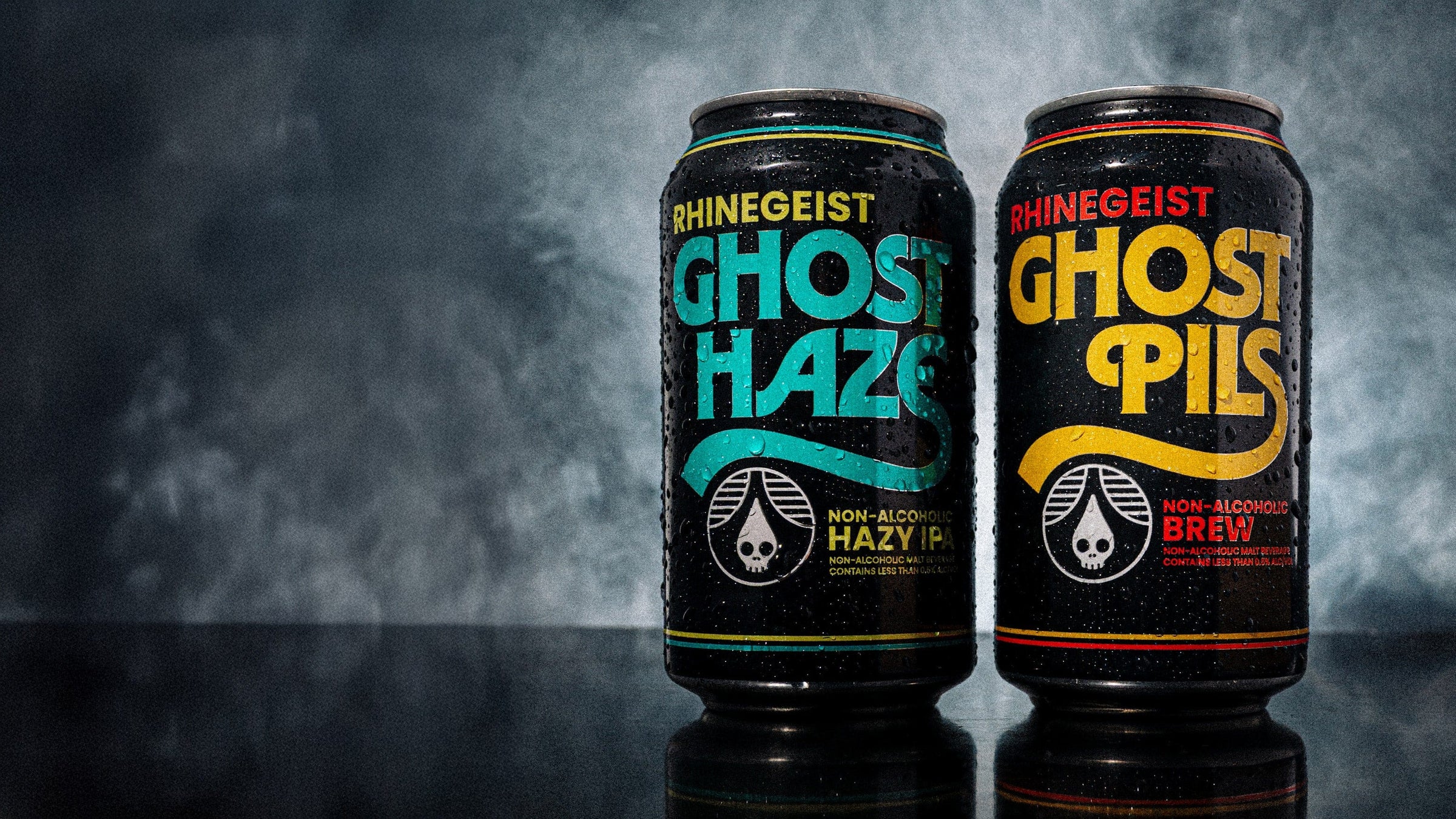 Two cans of Rhinegeist Ghost Haze and Ghost Pils non-alcoholic brews on a dark background.