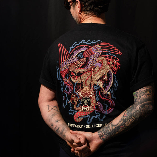 Person wearing a black t-shirt with a colorful dragon design on the back, against a dark background.