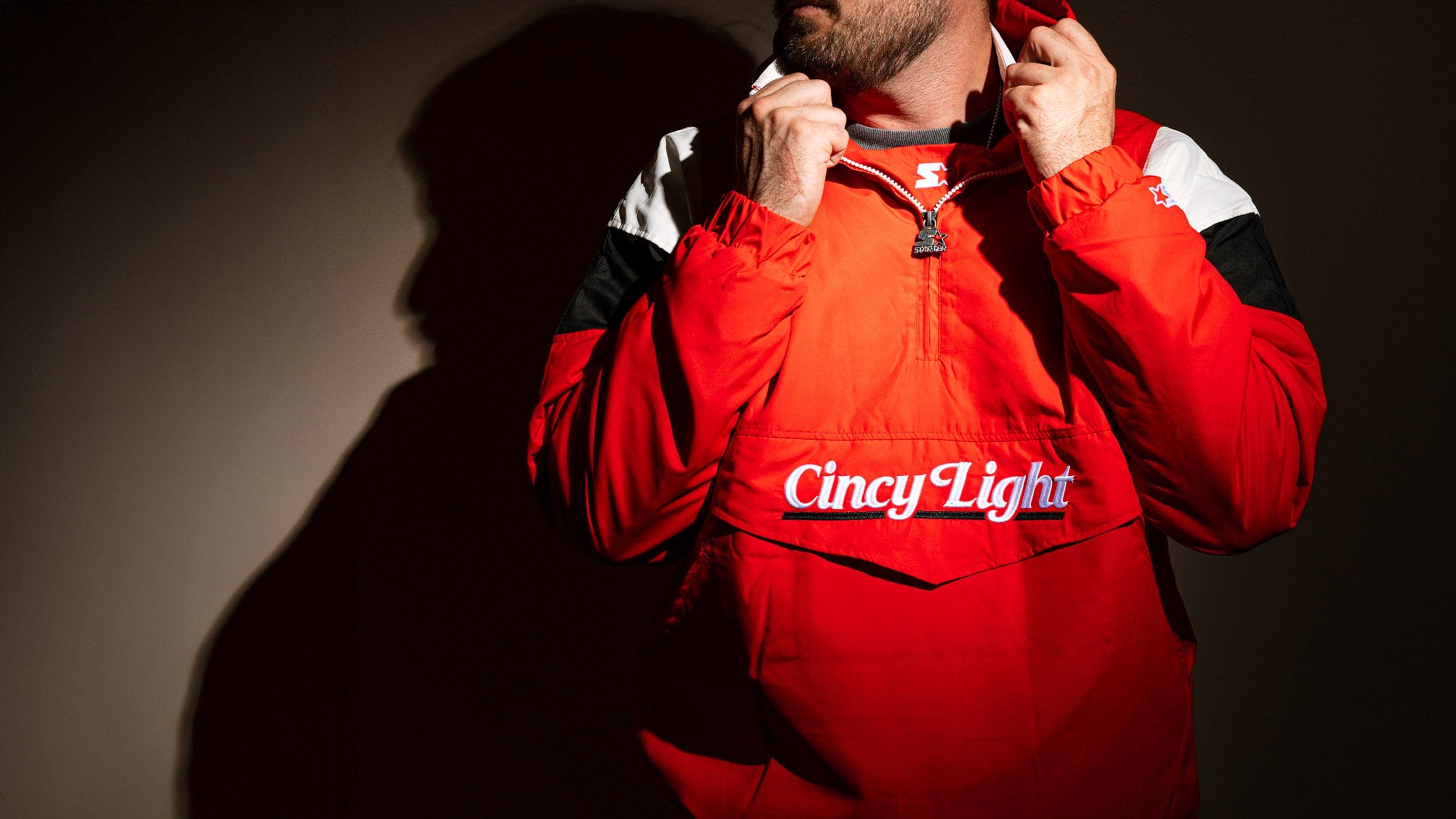 Person wearing a red jacket with 'Cincy Light' branding against a dark background